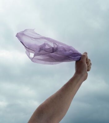 Someone holding a plastic bag in the wind with a gray sky behind. 