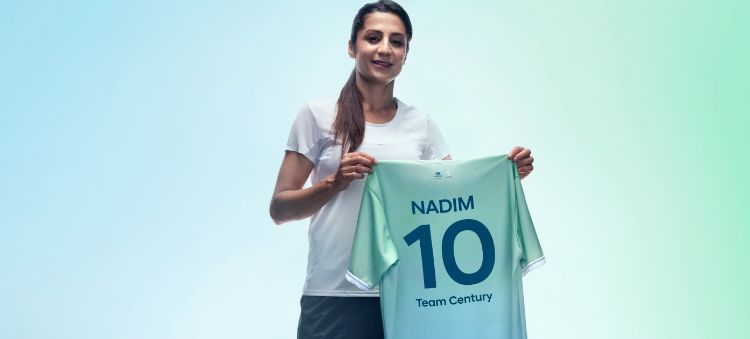 Danish footballer and Team Century member Nadia Nadim holding her green and blue Team Century shirt showing her name and the number 10.