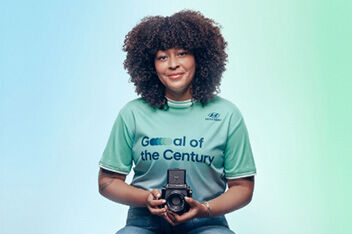 A close-up of Nicky Woo’s head and shoulders. Her hair is curly, and she is wearing a light green Team Century jersey with the Hyundai logo on it.