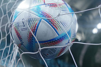 A white football with blue and red stripes hitting the back of a goal.