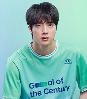 BTS member Jin wearing a green Team Century shirt.