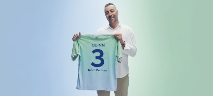 로렌초 퀸이 짙은 파란색 글씨로 “Quinn”, “3”, “Team Century”라고 적힌 녹색 및 하늘색의 팀 센츄리 유니폼을 들고 있습니다. 