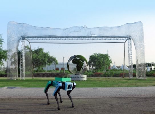 현대와 보스턴 다이내믹스의 4족 로봇 스팟(Spot)이 지구본 모양의 축구공이 가운데 있는 대형 축구 골대 앞에 서 있습니다.