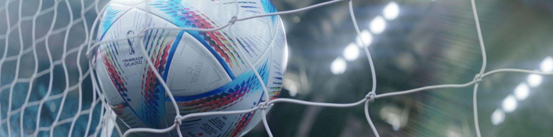 A white football with blue and red stripes hitting the back of a goal.